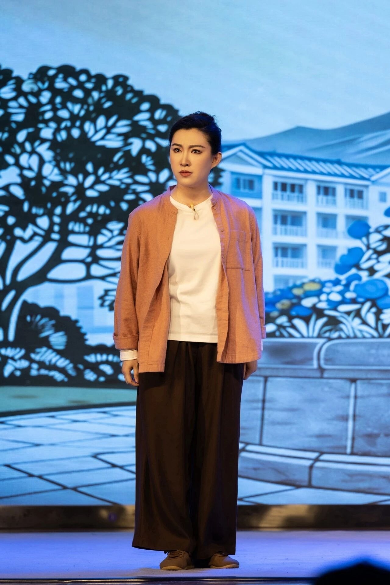 原创京剧《平凡之光》首演剧照：社区工作者形象（现代戏扮相，彩绘社区景片前）