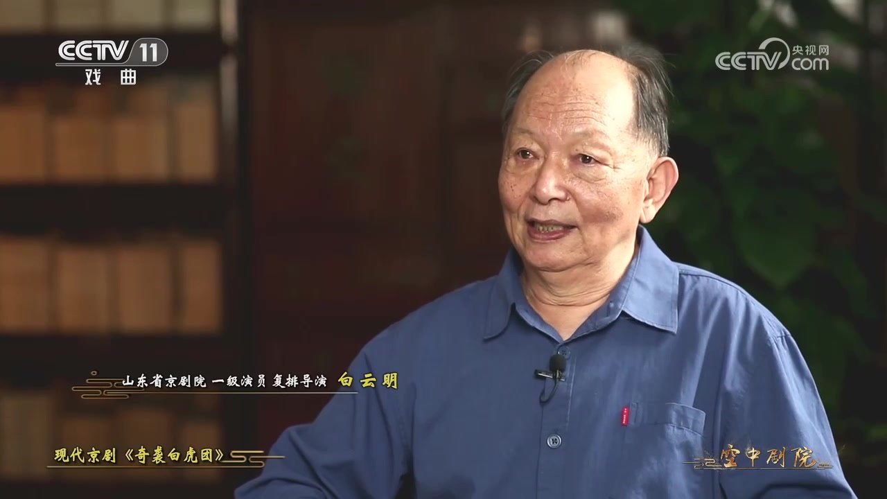 白云明受访截帧:画面左下姓名条作「山东省京剧院一级演员 复排导演 白云明」,题条作「现代京剧《奇袭白虎团》」