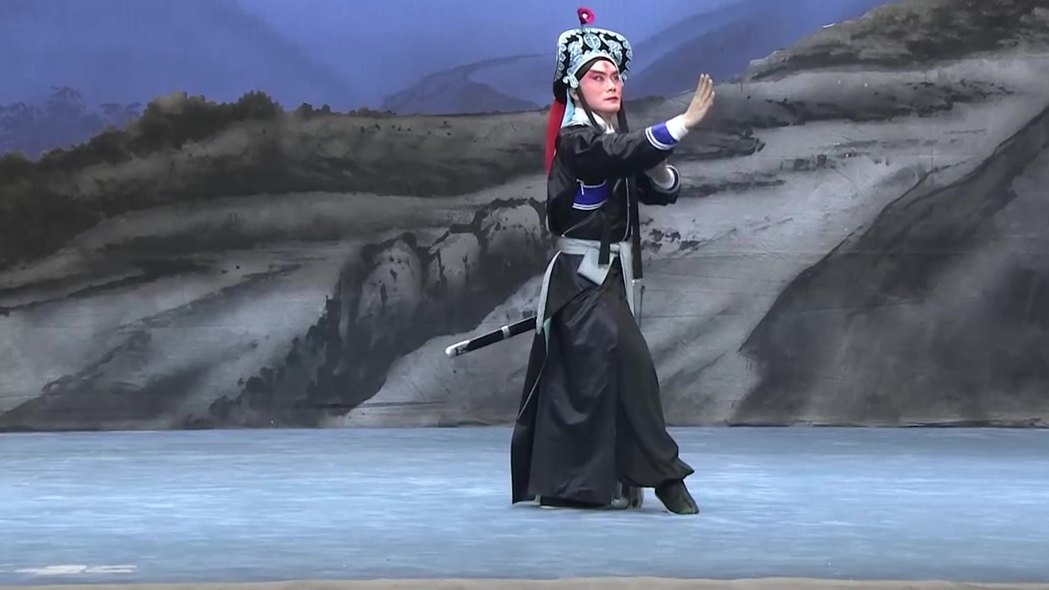 央视《中国京剧像音像集萃》20230915《林冲夜奔》演出影像截帧:黑箭衣、红绒球罗帽的林冲在山水天幕前亮相