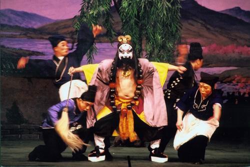 京剧《野猪林》剧照:鲁智深(净,勾脸、挂佛珠、着僧衣)居中,众角色环侍(国家京剧院官网剧目页所载)